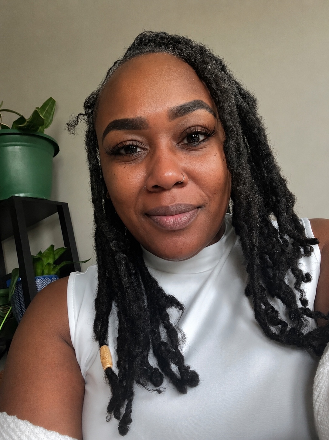 Marsita L. Ferguson in a white high-neck top, wearing her locs with a wooden bead